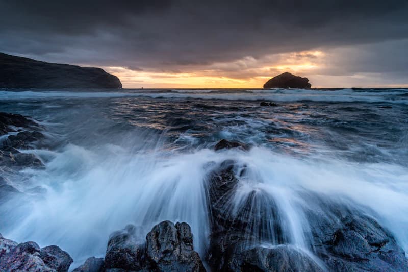 Ondas a rebentar na costa rochosa ao pôr do sol, São Miguel, Açores